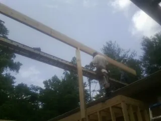 Carpenter setting a ridge beam over a new addition frame — Ice Dam Removal by Roofing Brothers in Newman Grove