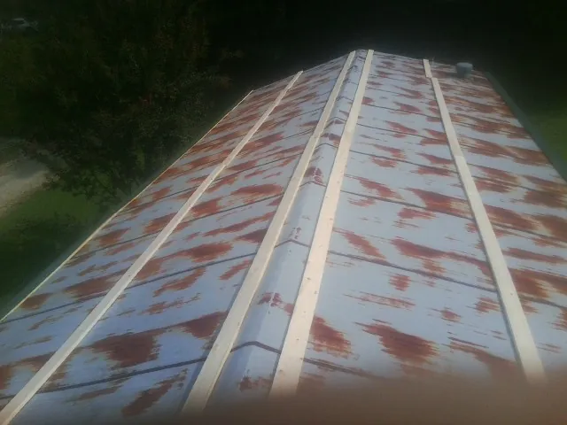 Rusted metal roof panels with new wood purlins before replacement — Storm Damage Roof Repair in Newman Grove by Roofing Brothers