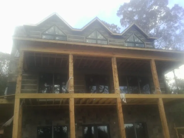 Dormers and porch framing on a large log home under construction — Roof Coating work by our crew in Newman Grove