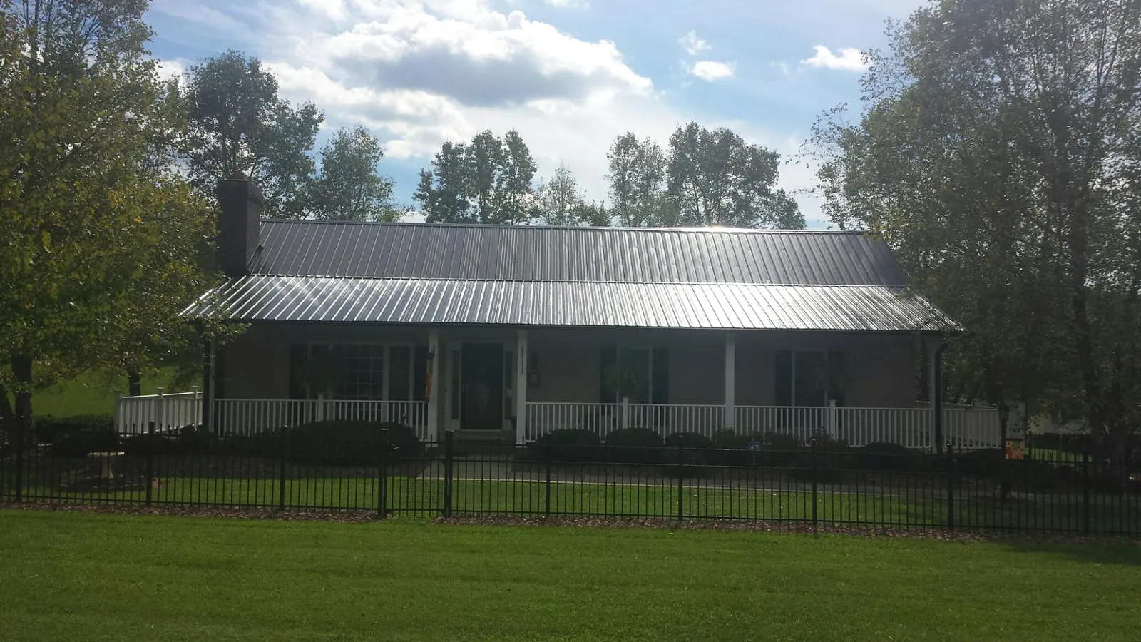 Gray metal roof on a brick ranch with a full width front porch — Gutter Guard Installation work by our crew in Newman Grove