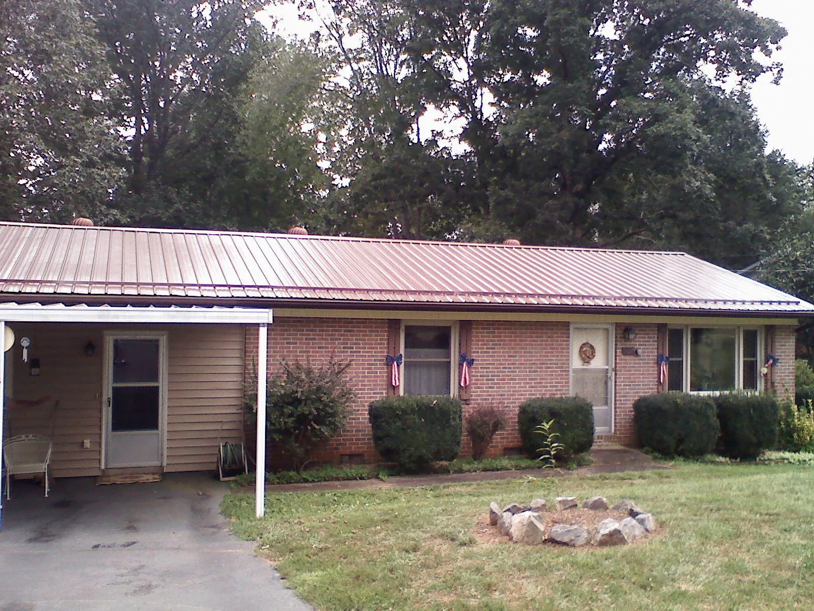 Bronze metal roof and carport on a brick ranch home — Roof Repair work by our crew in Newman Grove