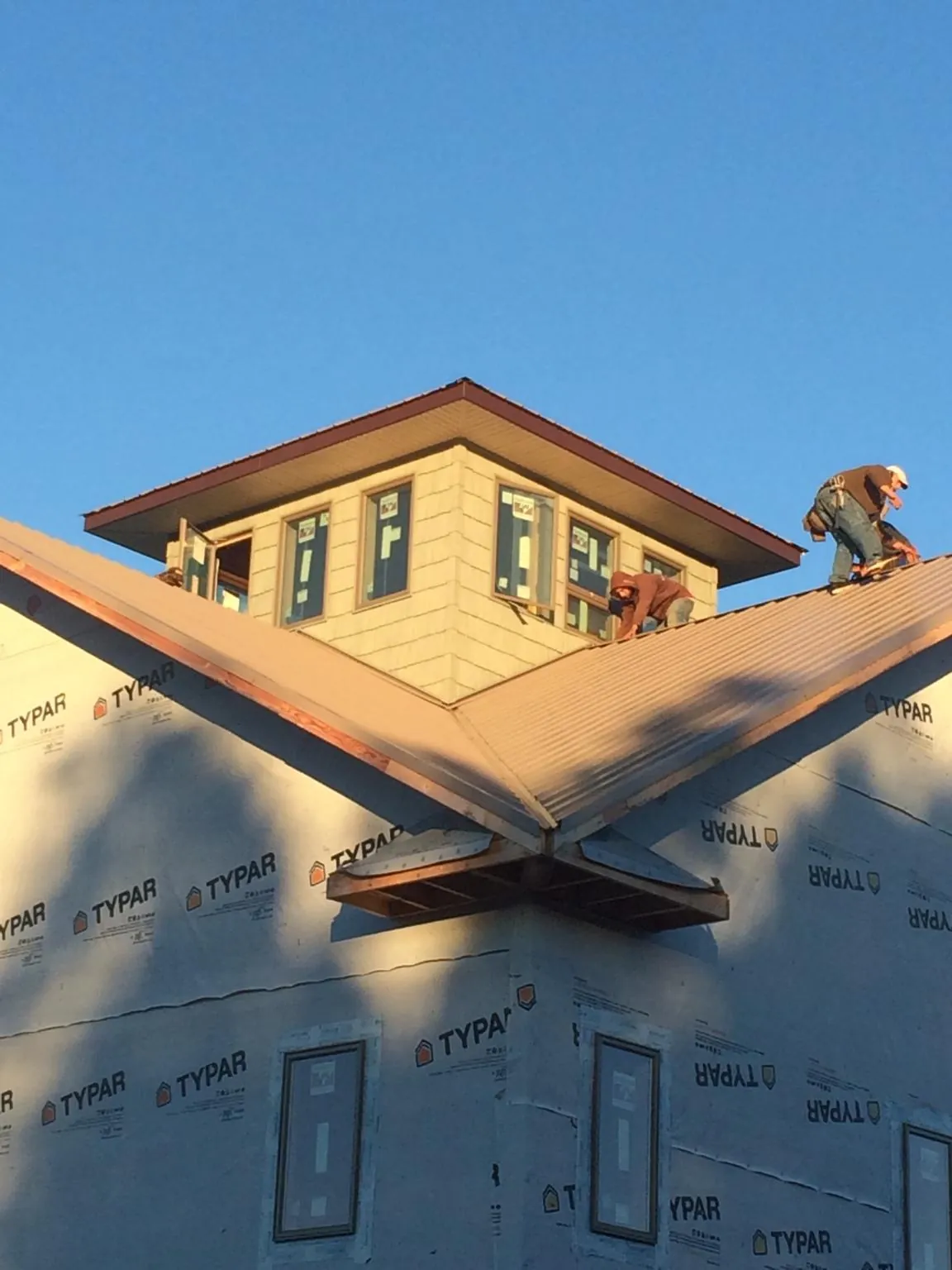 Roofers working around a rooftop cupola on a new metal roof at sunset — Roof Waterproofing in Newman Grove by Roofing Brothers